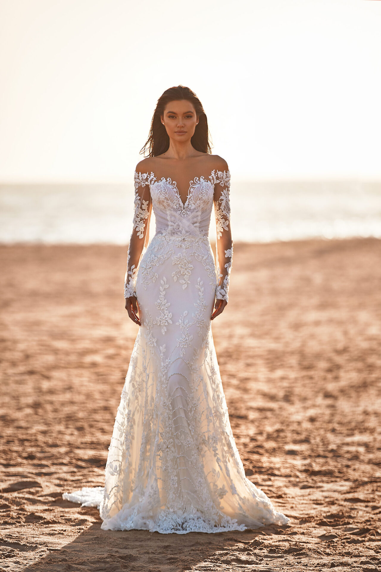 A woman in a white dress standing on the beach.