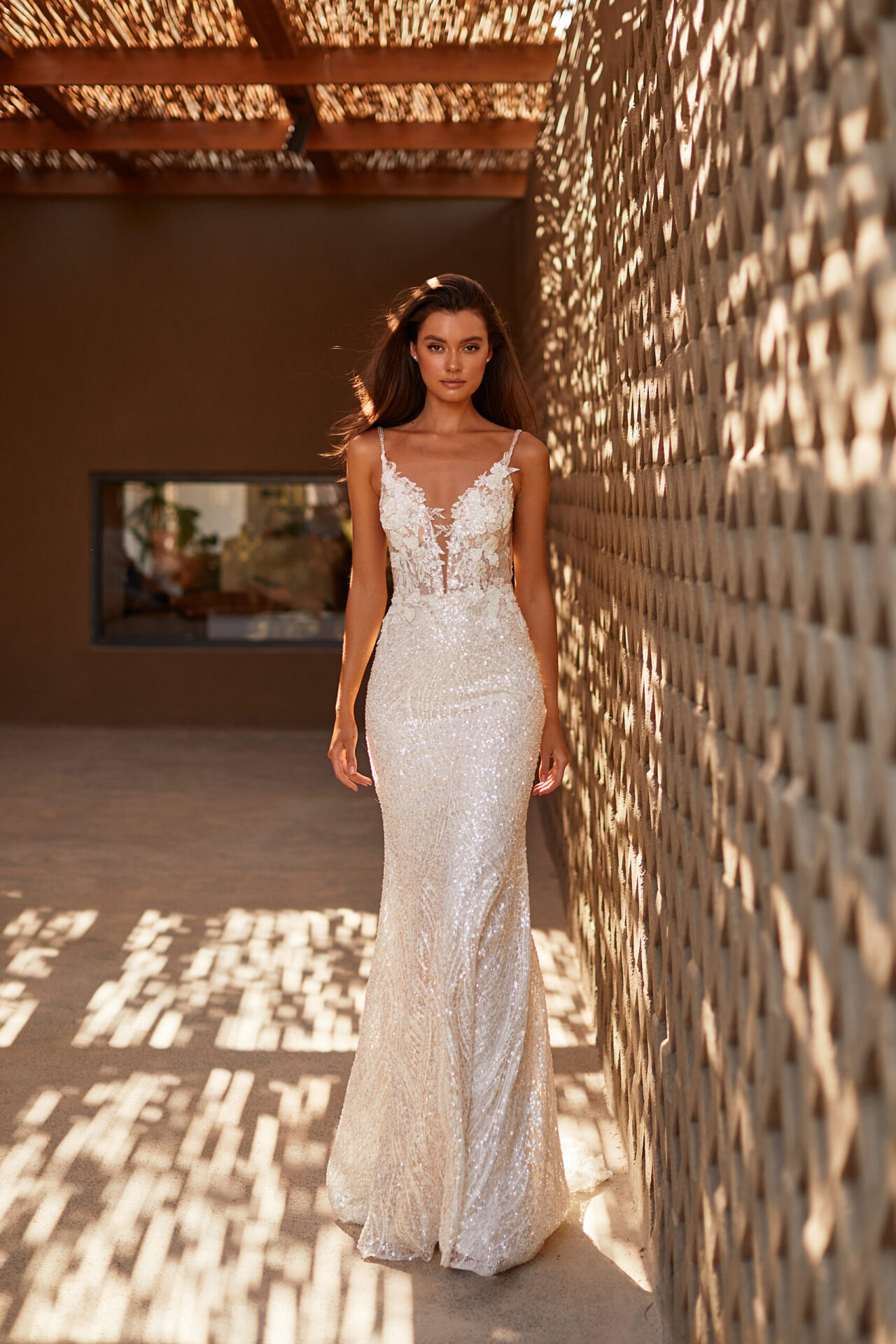 A woman in a white dress standing next to a wall.